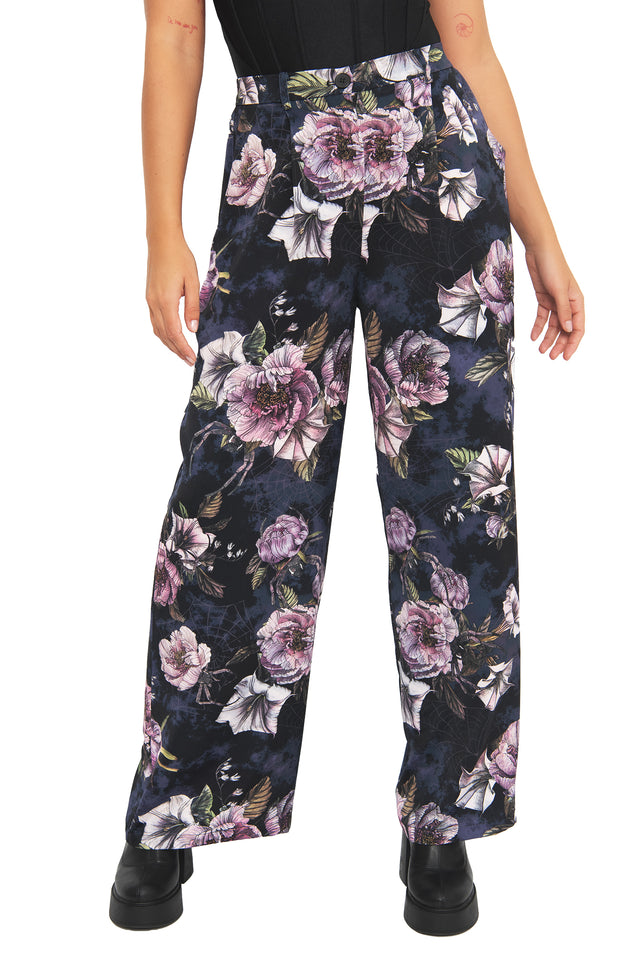 Dark academia floral pants with moody botanical artwork and subtle hidden spider details woven through the print. These corporate goth trousers combine alternative office fashion and modern witch aesthetics with a relaxed flowing silhouette.
