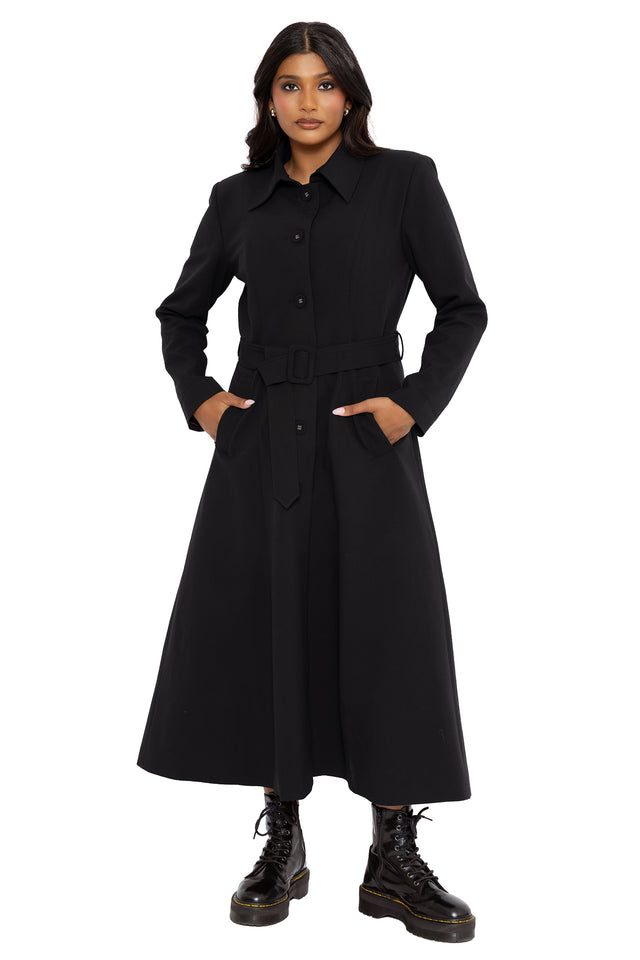 Minimalist gothic trench coat in all black with structured tailoring, welt pockets and a removable cape feature. Designed for corporate goth wardrobes, this alternative witch coat combines dark academia and modern gothic fashion with hidden mystical details.