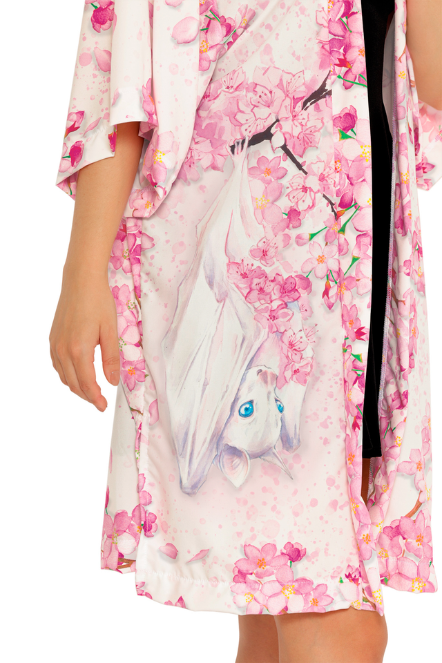Pearl in Sakura Robe featuring loose kimono-style sleeves and a knee-length cut, styled open over a black dress.