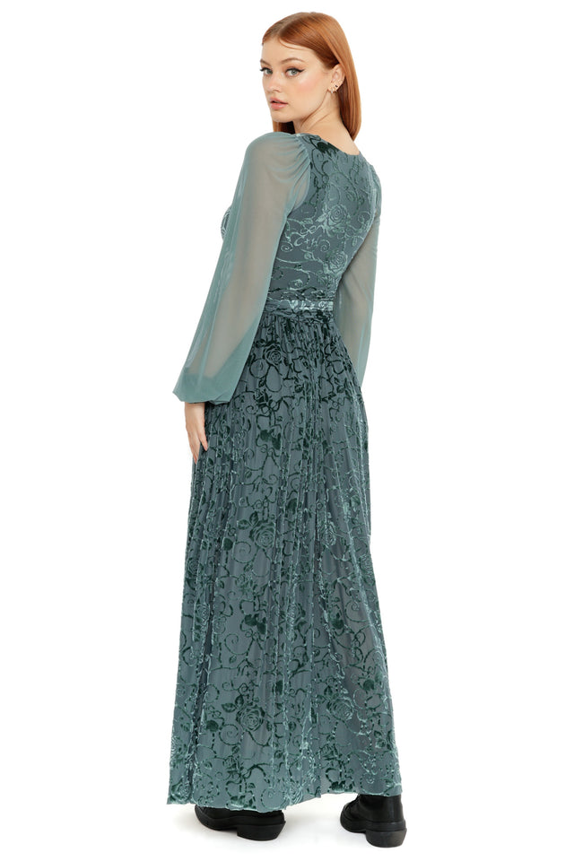 Model styled in the Be With Me Always Juniper Burned Velvet Sheer Romance Maxi Dress, featuring a fitted bodice, sheer long sleeves and soft velvet floral texture