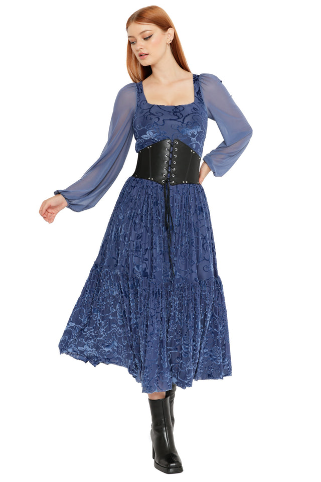 Model wearing the Be With Me Always Slate Burned Velvet Fae Queen Dress from the Wuthering Heights collection, featuring a square neckline, sheer long sleeves, slate blue burned velvet floral fabric and a flowing tiered midi skirt