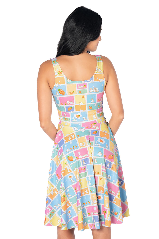 Cute bunny print longline tee dress showcasing whimsical rabbit postage stamp artwork, pastel colours, carrots and cloud illustrations with a comfortable relaxed fit and pockets.