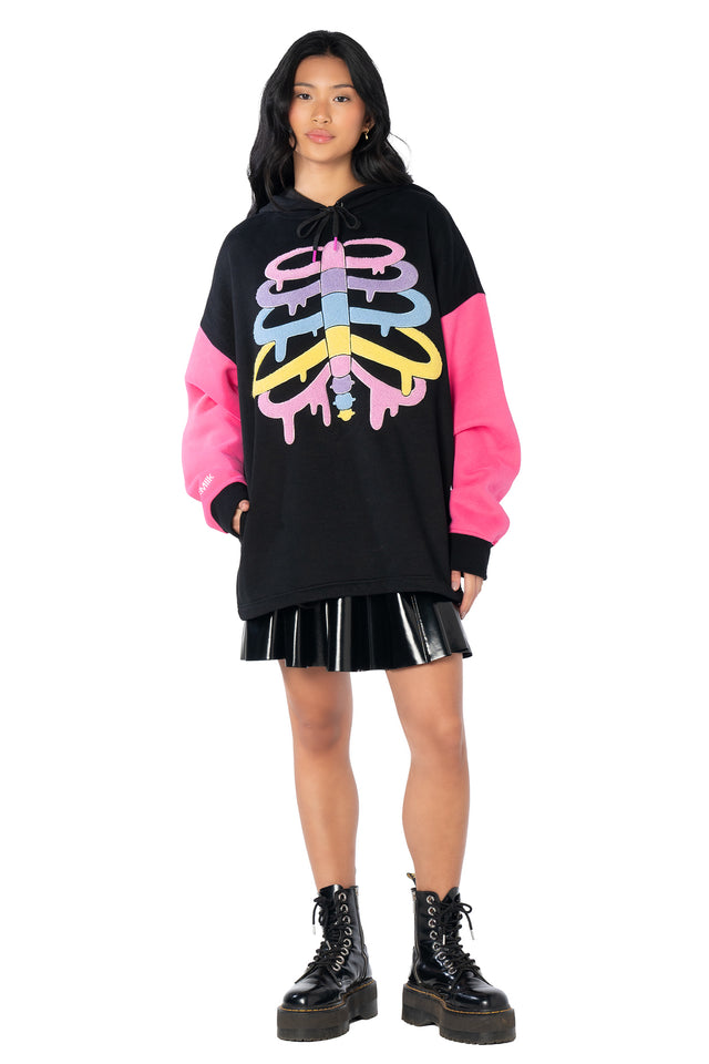 Cosy oversized fleece hoodie featuring a colourful skeleton graphic, vibrant pink sleeves, embroidered BlackMilk logos and a relaxed streetwear-inspired unisex silhouette.