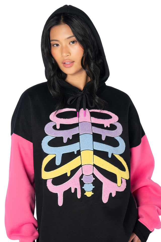 Alternative oversized fleece hoodie with colourful skeleton artwork, hot pink sleeves, embroidered BlackMilk branding and a relaxed unisex fit for cosy streetwear styling.