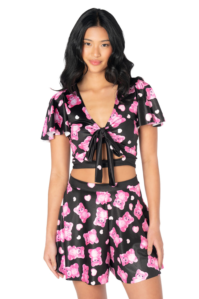 Alternative cropped Rio top showcasing colourful gummy bear skeleton illustrations, shiny stretch fabric, flounced sleeves and a versatile removable tie that can also be worn as a bow or hair accessory.