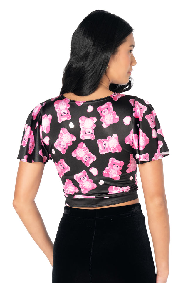 Statement cropped top with colourful gummy bear skeleton print, shiny stretch fabric, flutter sleeves, front cut-out neckline and a removable tie for party-ready alternative fashion.