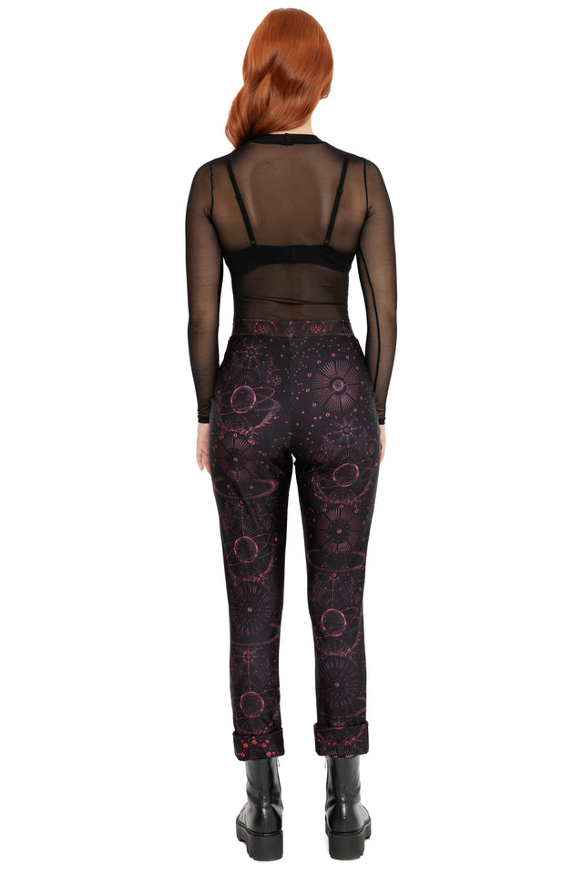 Cosmic print cuffed pants in black with red starburst and planet details, styled with a relaxed tapered leg