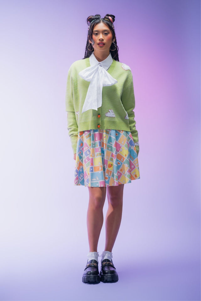 Green cropped knit cardigan featuring an all-over bunny pattern, carrot-shaped buttons and ultra-soft yarn for a cosy cottagecore-inspired layering piece.