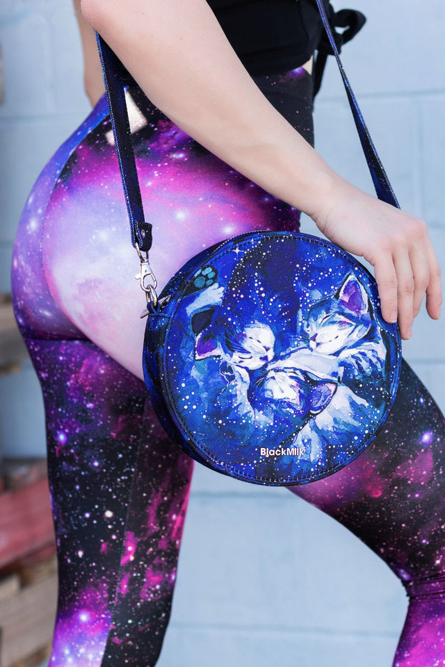 Person wearing galaxy-themed leggings with a matching round bag featuring angel and cat design.