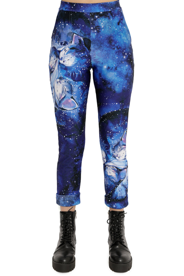 Blue galaxy-themed pants with cat designs worn by a person on a white background