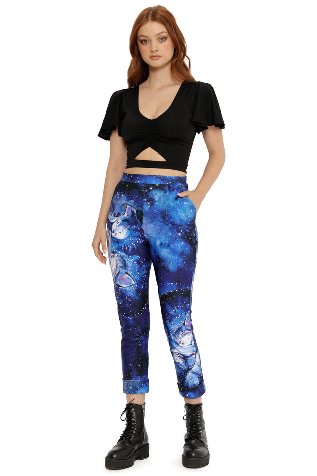 Woman wearing a black crop top and blue galaxy-patterned leggings on a white background