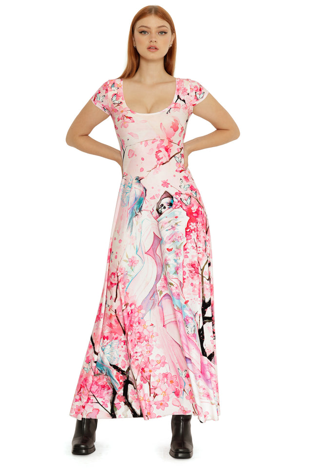 Front view of the Death’s Friend Cap Sleeve Maxi Dress featuring a soft pink base with illustrated florals, butterflies, and flowing character artwork.