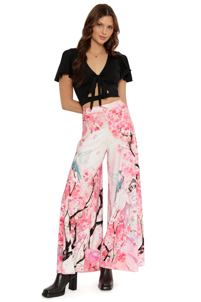 Woman wearing a black top and pink floral pants on a white background