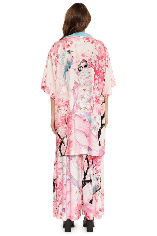 Woman wearing a kimono-style dress with cherry blossom and bird design on a white background