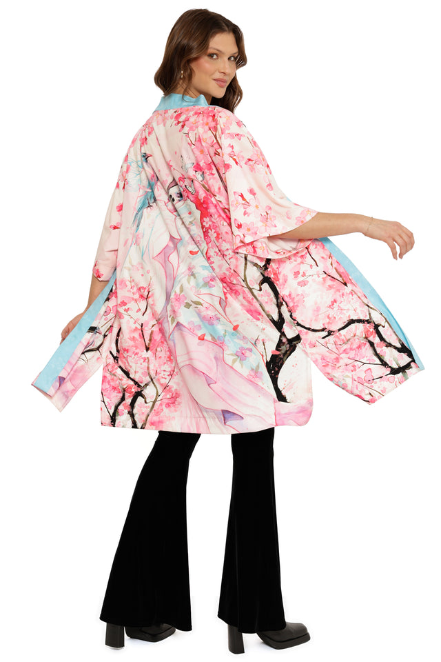 Woman wearing a pink kimono with cherry blossom design on a white background