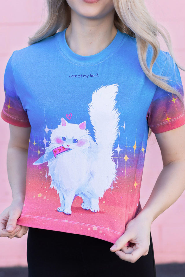 Person wearing a blue t-shirt with a cartoon cat design on a pink background