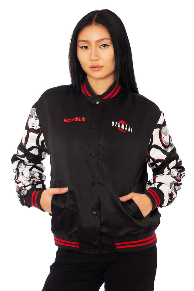 Uzumaki satin varsity jacket by Junji Ito x BlackMilk with bold red spiral vortex graphic on the back and manga panel sleeves in gothic anime streetwear style.