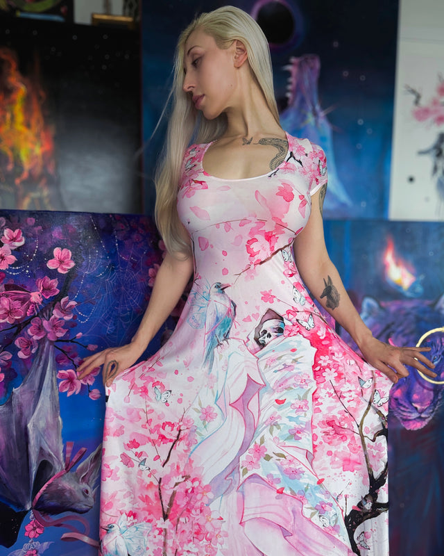 Lora Zombie in a pink floral dress sitting on a colorful couch with abstract art in the background
