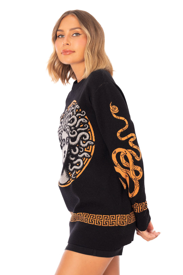 Medusa Crew Knit Sweater front view showing an oversized black crew neck knit sweater with large Medusa graphic on the front, orange Greek key border at hem and mythology inspired snake artwork on the sleeves