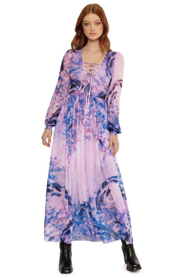 Model wearing a long, floral-patterned dress on a white background