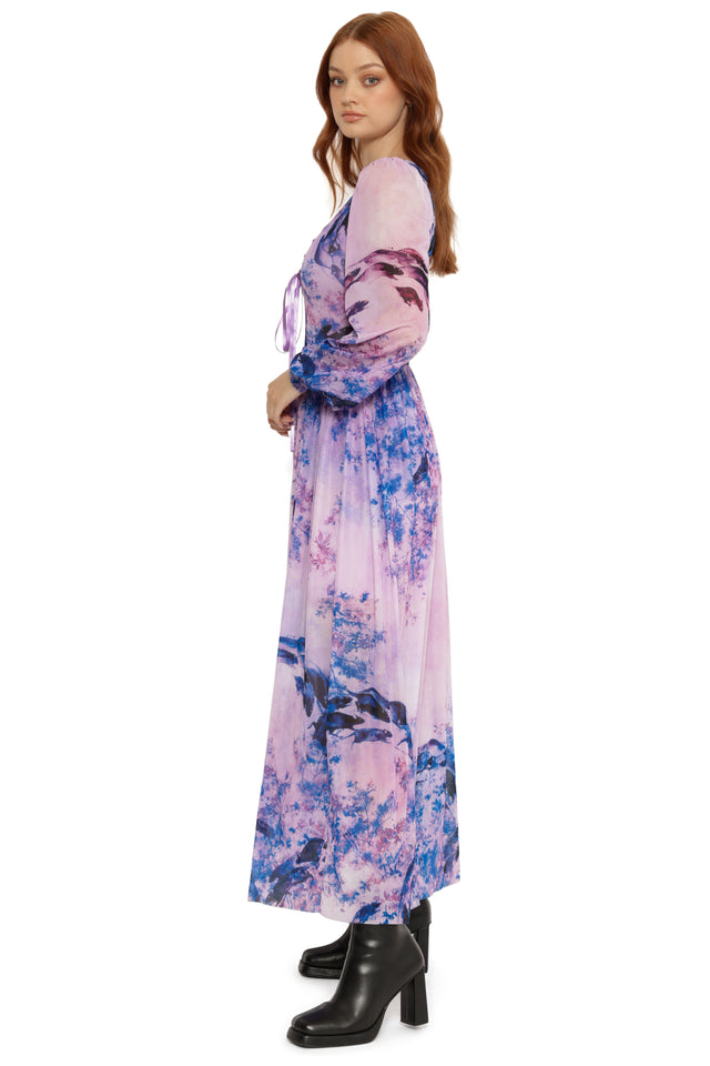 Woman wearing a long, floral-patterned dress on a white background