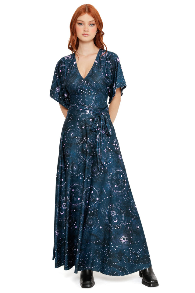 Model wearing a navy wrap maxi dress with celestial chart print, featuring moons, stars and constellation details.