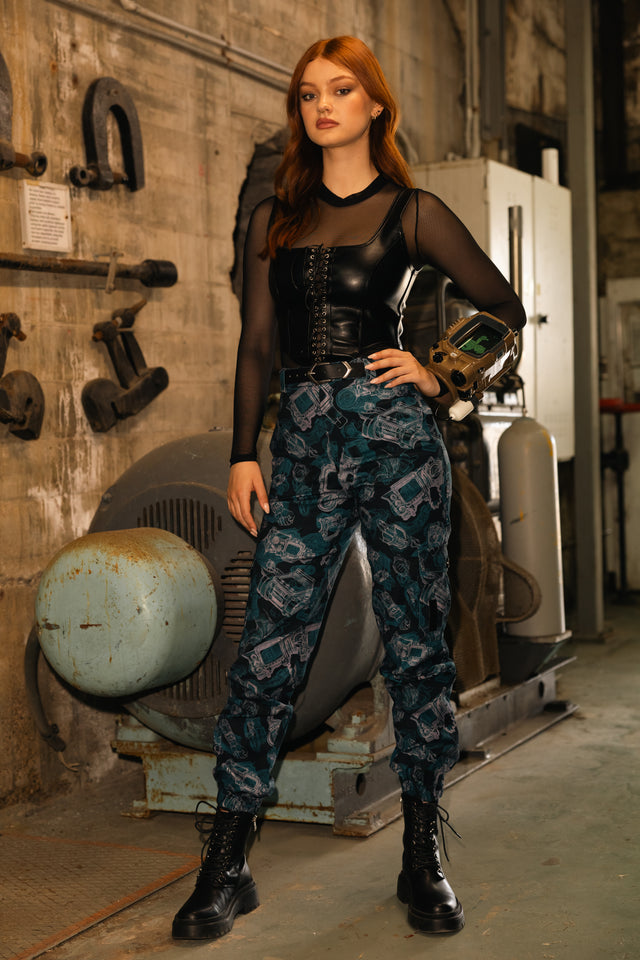 Model wearing Fallout x BlackMilk Pip-Boy Schematics Cargo Pants featuring all-over Pip-Boy blueprint print in blue tones.