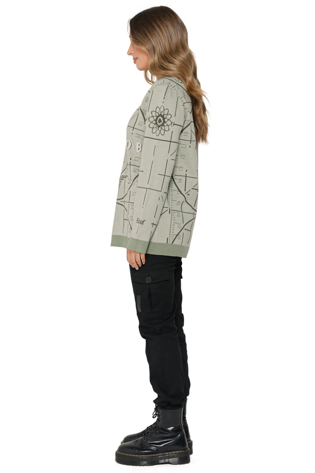 Model wearing Fallout x BlackMilk Please Stand By Oversized Knit Sweater in sage green featuring retro Fallout test screen design.