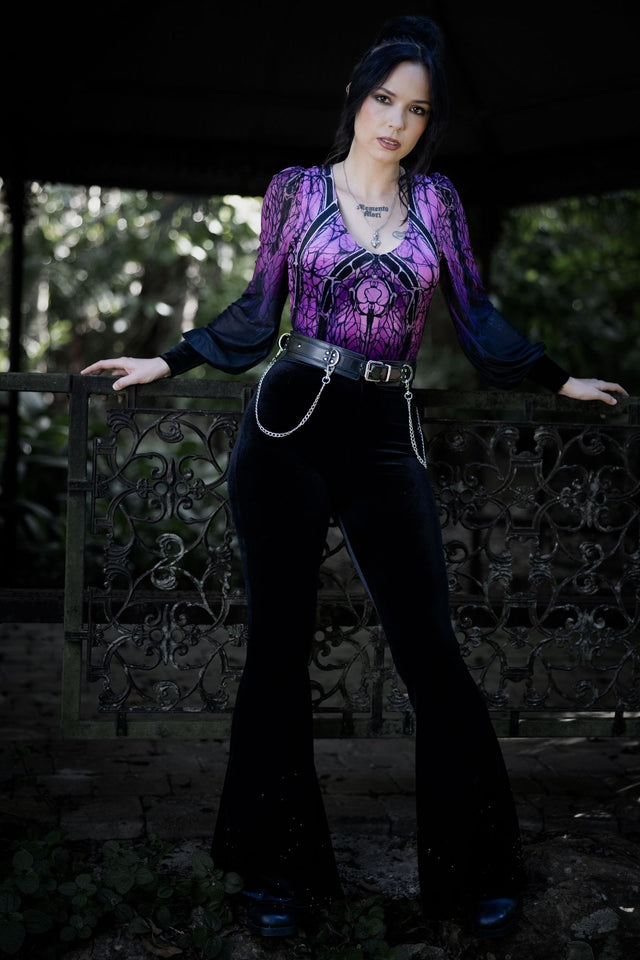 Gothic velvet bodysuit with cathedral-inspired spider web artwork in vivid purple and black tones, featuring sheer mesh bishop sleeves and a flattering V neckline. This whimsigoth bodysuit blends dark fairycore, gothic fashion and fantasy witch aesthetics for an elegant alternative witchcore look.