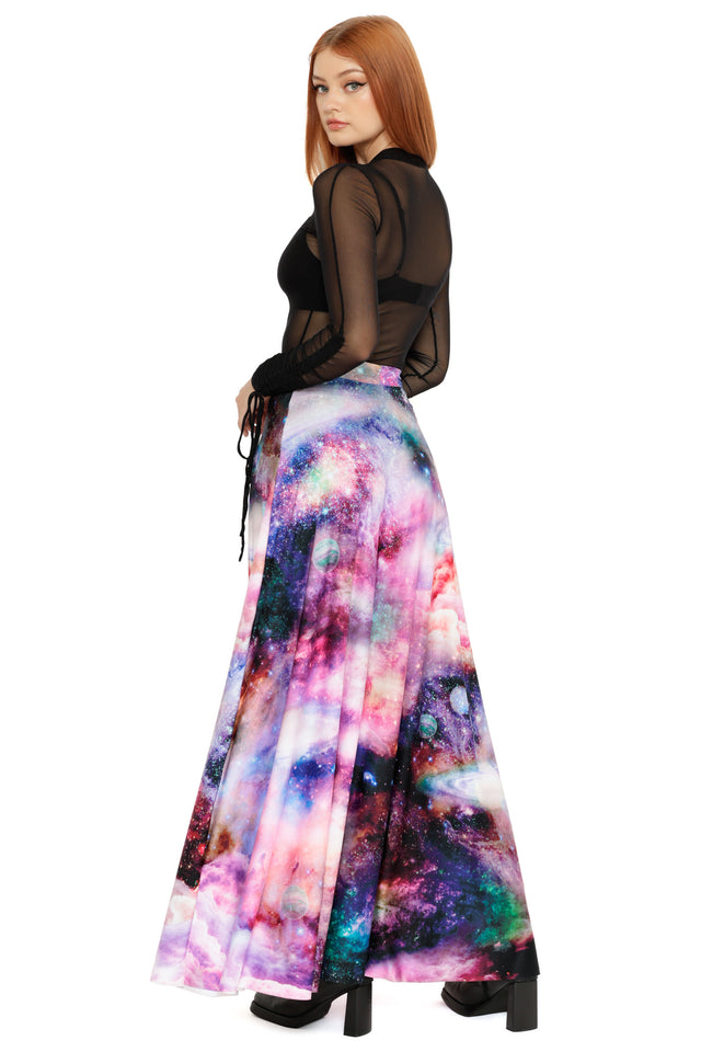 Model styled in a sheer black top layered over a bralette, paired with a vibrant pastel galaxy print maxi skirt