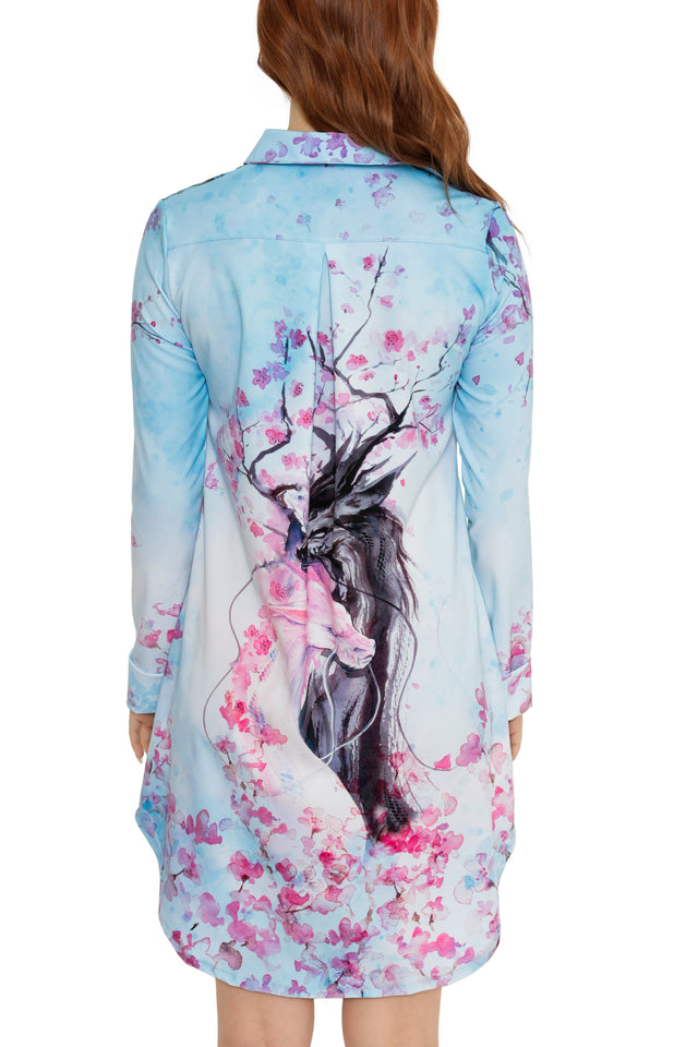 Woman wearing a floral dress with a deer and cherry blossom design on a white background