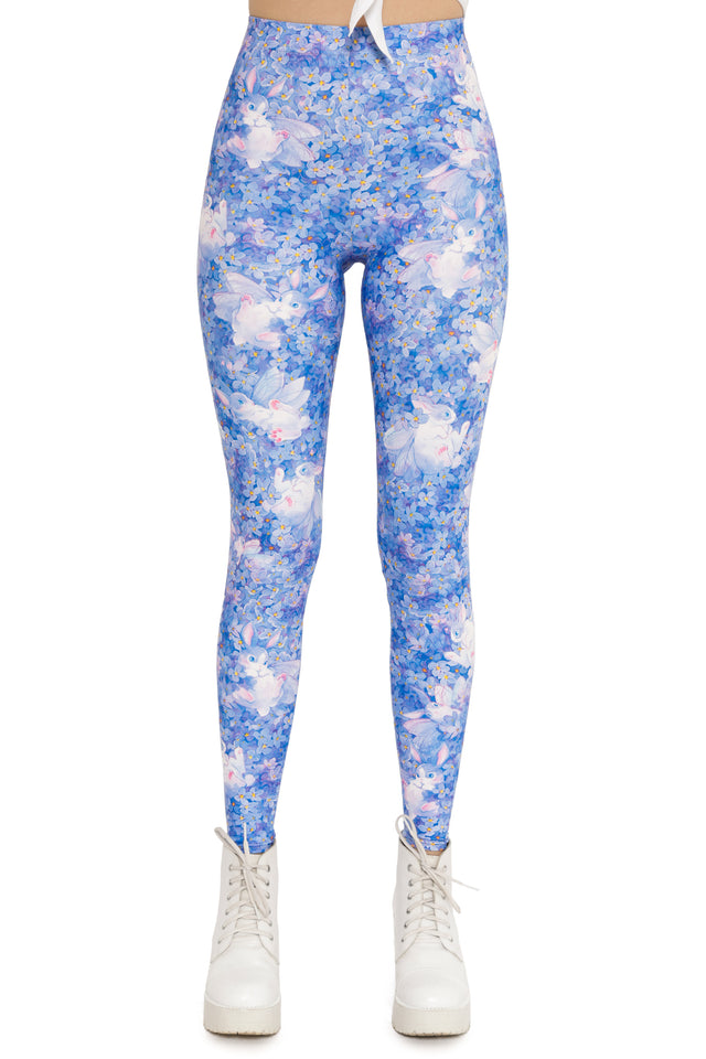 Blue floral leggings worn with white sneakers on a white background