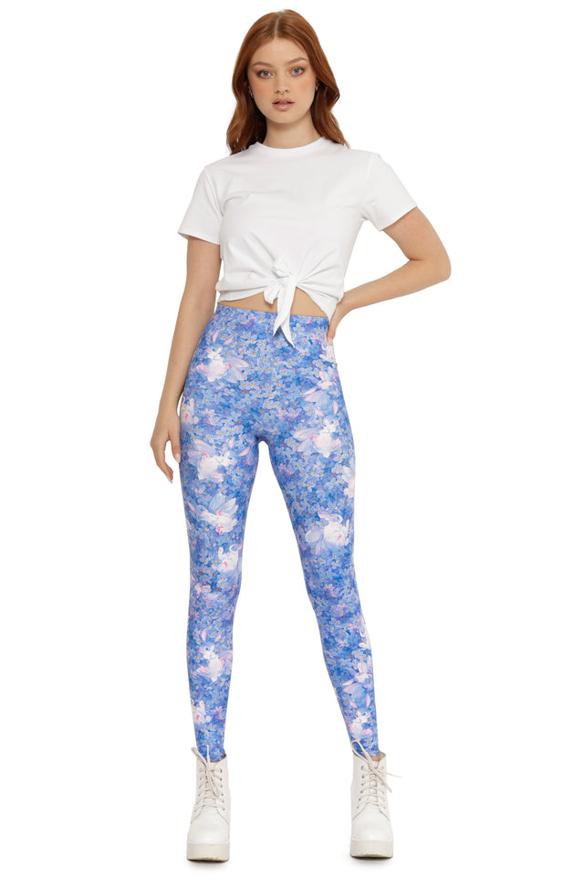 Woman wearing a white crop top and blue floral leggings on a white background