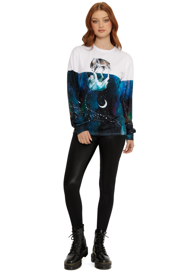 Person wearing a white long sleeve t-shirt with a graphic design of a wolf and moon, black leggings, and black boots on a white background.