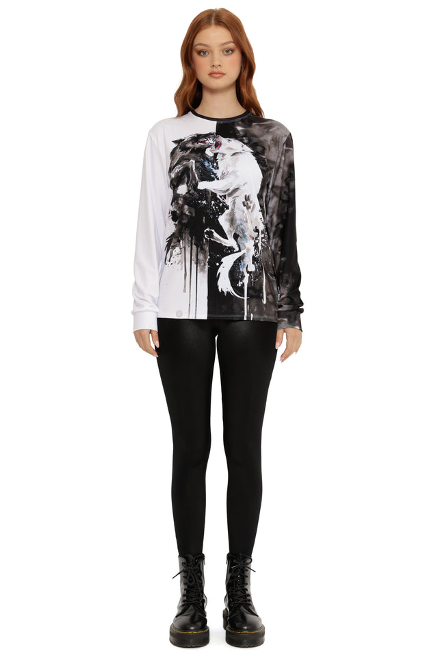 Model wearing a black and white graphic long-sleeve shirt with black pants on a white background