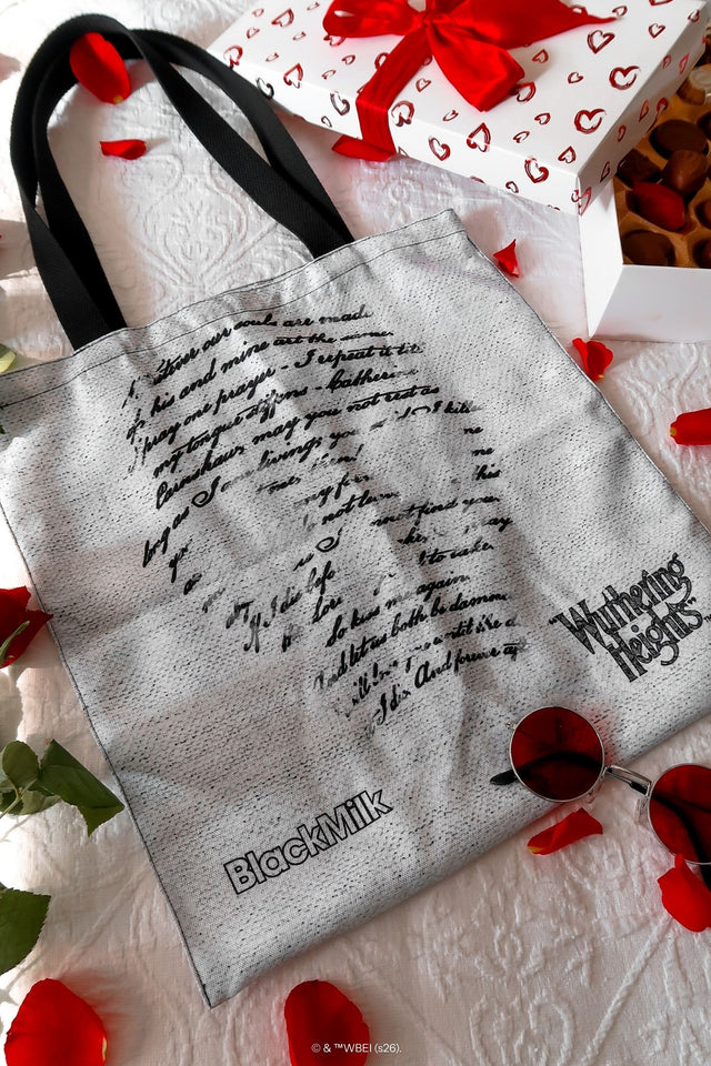 Front view of the Drive Me Mad Tote Bag, a gothic grey tote from the Wuthering Heights collection with bold script lettering and black straps