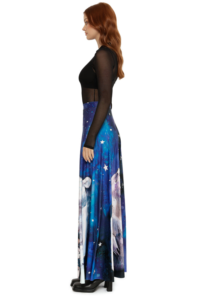 Woman wearing a black top and blue skirt with celestial design on a white background