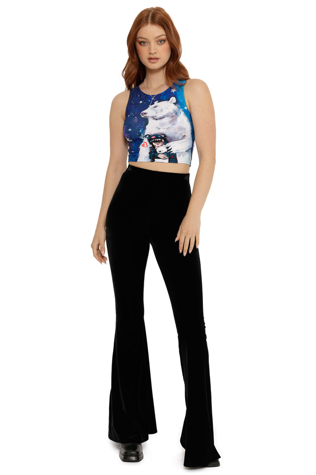 Woman wearing a sleeveless top with a bear graphic and black flared pants on a white background