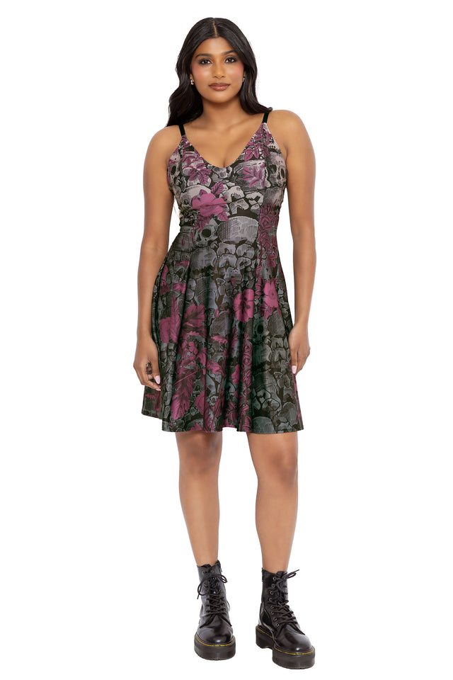 Soft goth longline strappy dress featuring romantic florals blooming through catacomb inspired skull artwork. Designed with a fitted bodice and elongated silhouette, this fantasy witch dress captures dark romantic and alternative gothic fashion vibes.