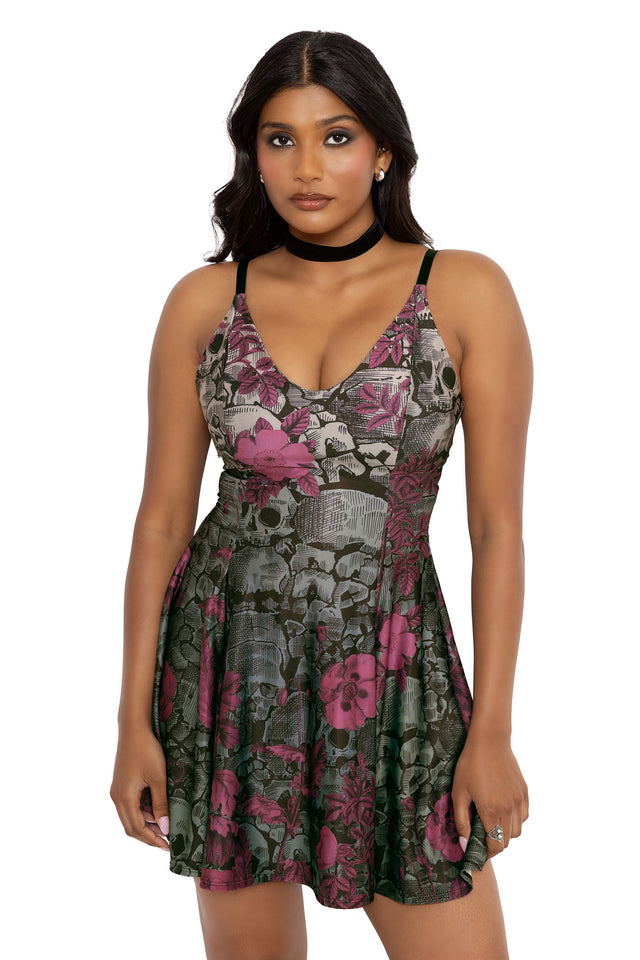 Alternative goth mini dress featuring pink florals layered over gothic skull artwork inspired by the Paris Catacombs. Designed with a V neckline, fitted bodice and twirl-worthy skater skirt, this fantasy witch dress captures soft goth and dark romantic fashion vibes.