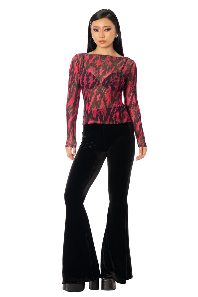 Model wearing the black and red graphic top with flared black trousers. League of Legends K/DA x BlackMilk black and red sheer long-sleeve top with Akali-inspired graphic artwork, a wide boat neckline and a relaxed fit.