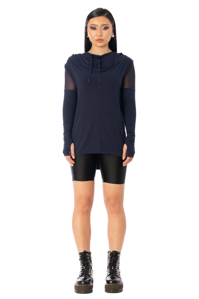 Model wearing the navy hooded Rogue Ninja top with black shorts. League of Legends K/DA x BlackMilk navy hooded Rogue Ninja top with relaxed sleeves and layered sporty styling.