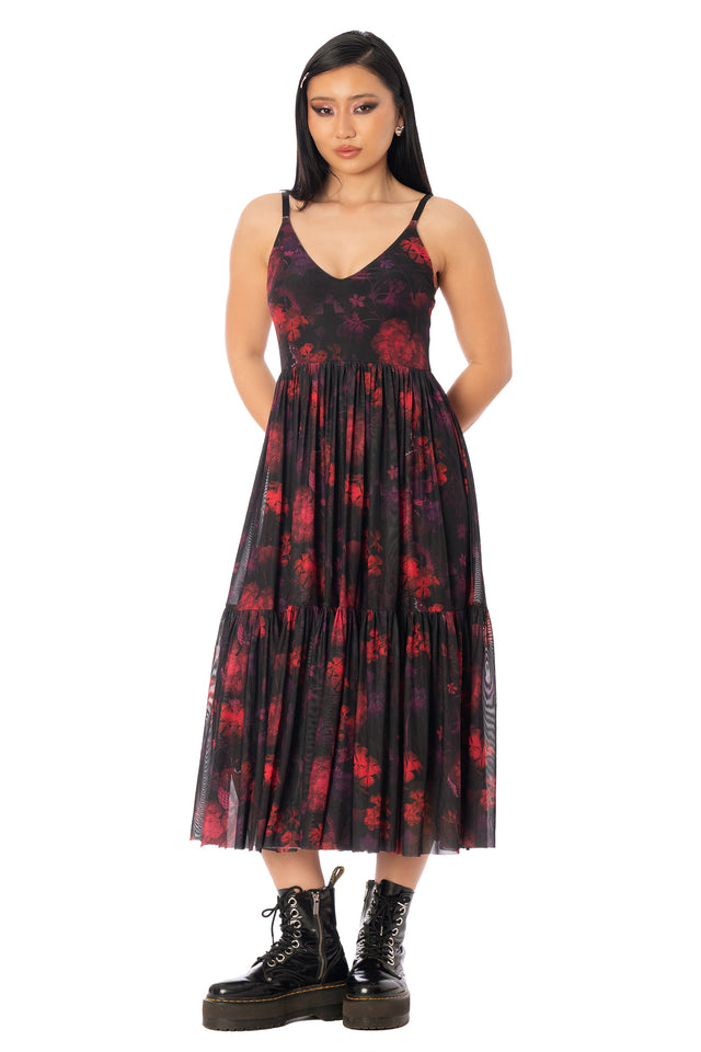 Model wearing the sheer red-and-black patterned midaxi dress over a dark underlayer. League of Legends K/DA x BlackMilk sheer mesh midaxi dress featuring red and black Evelynn-inspired snake artwork.