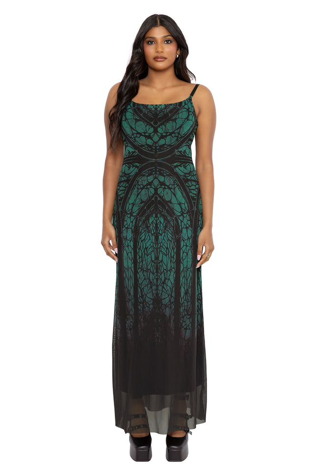Whimsigoth sheer maxi dress with stained glass inspired spider web artwork and flowing mesh layers in moody green and black tones. This gothic dress blends dark fairycore and fantasy witch fashion with a romantic cathedral inspired silhouette.