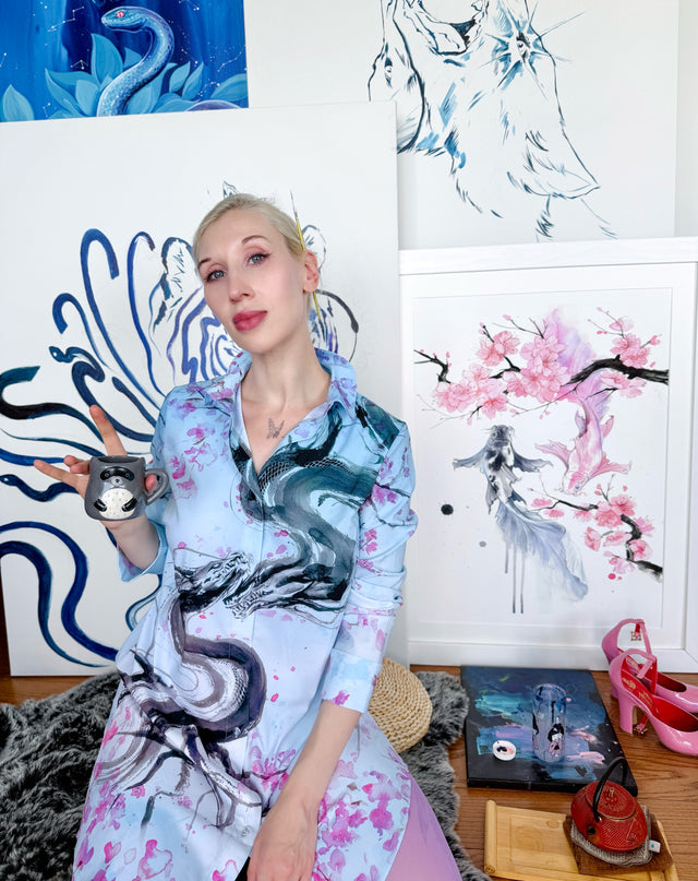 Person wearing a colorful dress with dragon design in an artistic room.