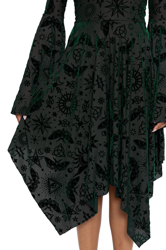 Dark fairycore handkerchief dress featuring occult symbols, stars, moons and mystical witch artwork across soft burned velvet fabric. This alternative witch dress blends gothic fashion and modern pagan aesthetics with dramatic bell sleeves and an elegant flowing silhouette.